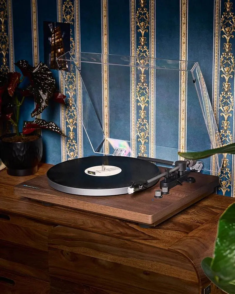 Plattenspieler mit Bluetooth Blaupunkt Torino TT 200 TX auf Holzkommode mit geöffneter Abdeckung vor blau-goldenem Musterhintergrund